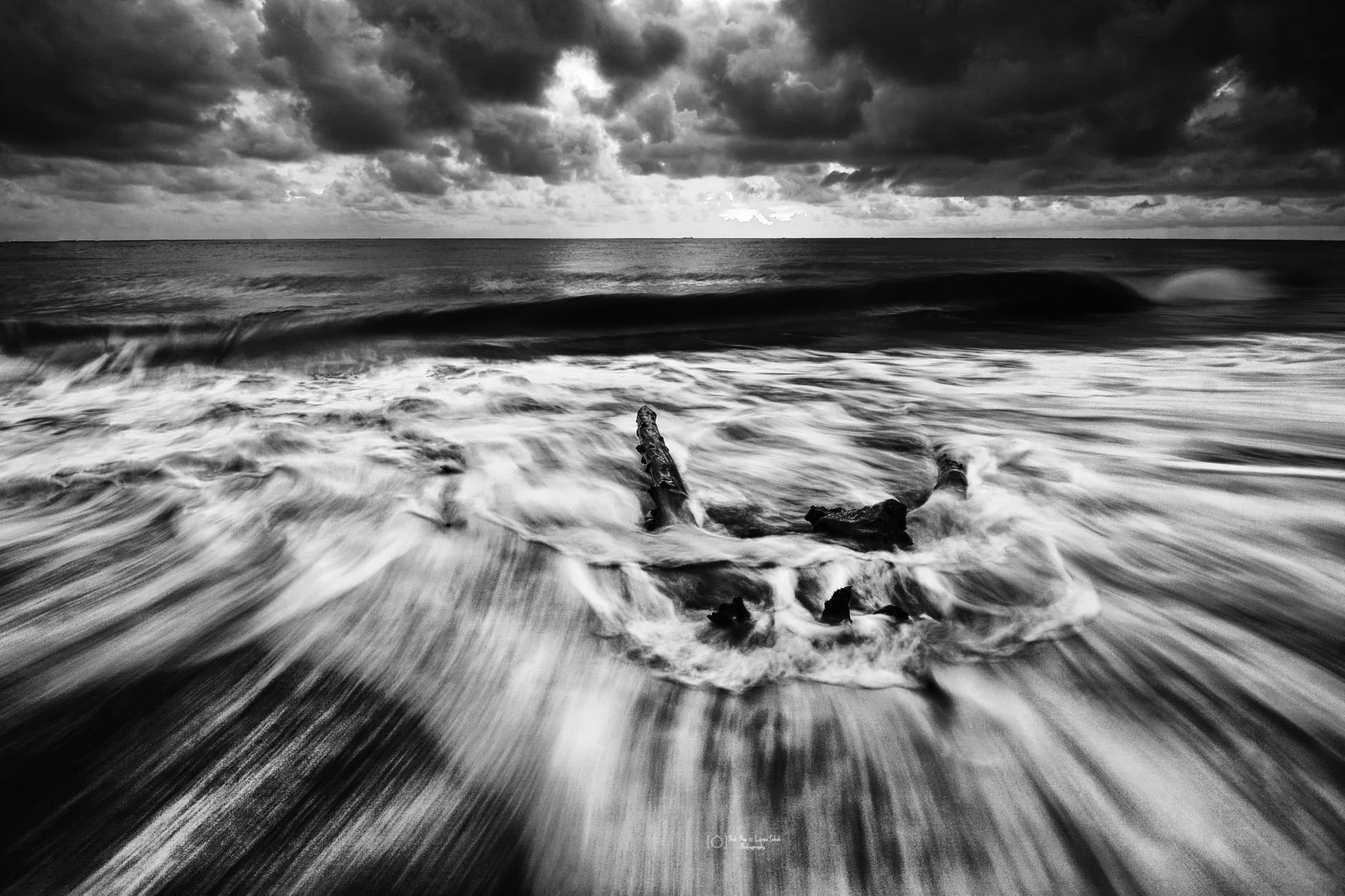 Long exposure captures dramatic waves under stormy skies by the ocean.